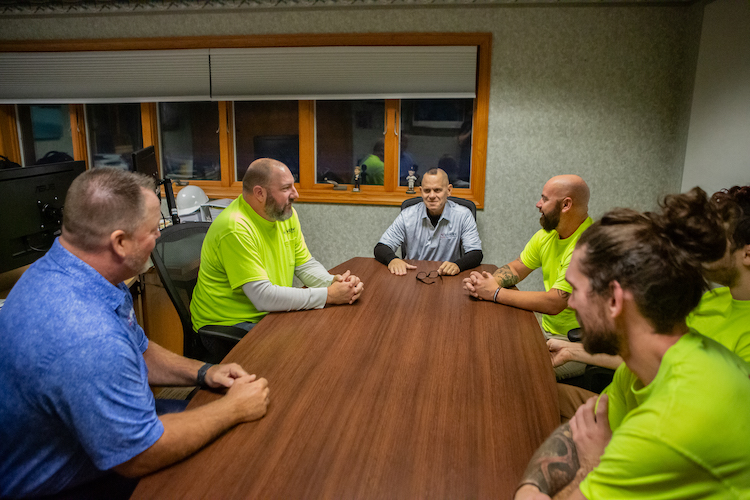 Six Henry Heating, Cooling, and Plumbing staff members sitting around a table having a meeting.