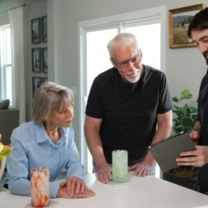 A couple is meeting with an HVAC technician to discuss repairing or replacing their HVAC system.